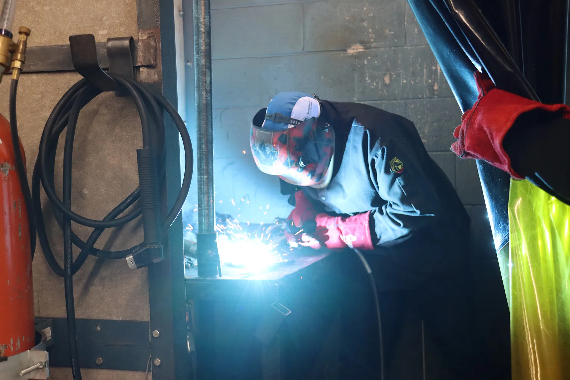 student in Welding Level 1 OYAP program at SNP Secondary School wearing protective gear and using a welding torch