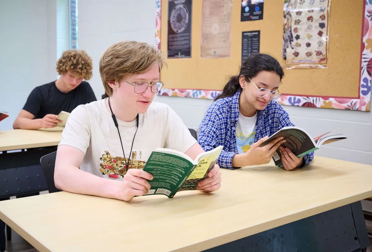 Young men reading a book in a classroom