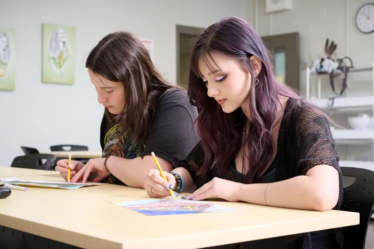 Young women drawing, sitting next to each other, having an art class