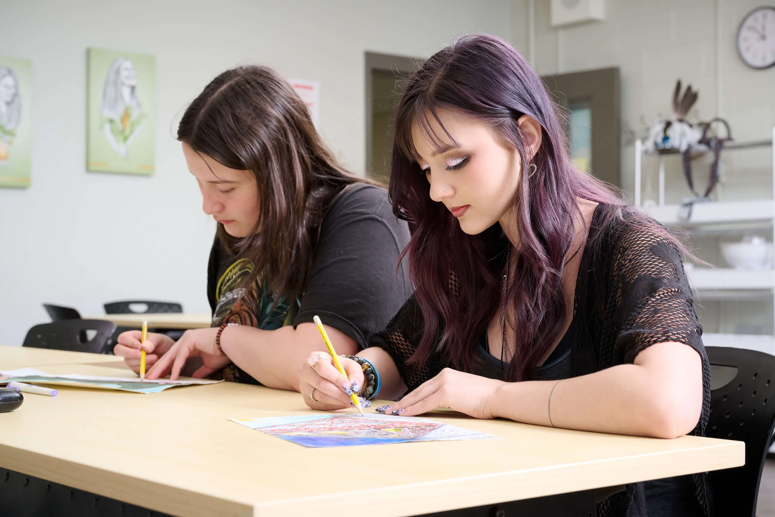 Young women drawing, sitting next to each other, having an art class