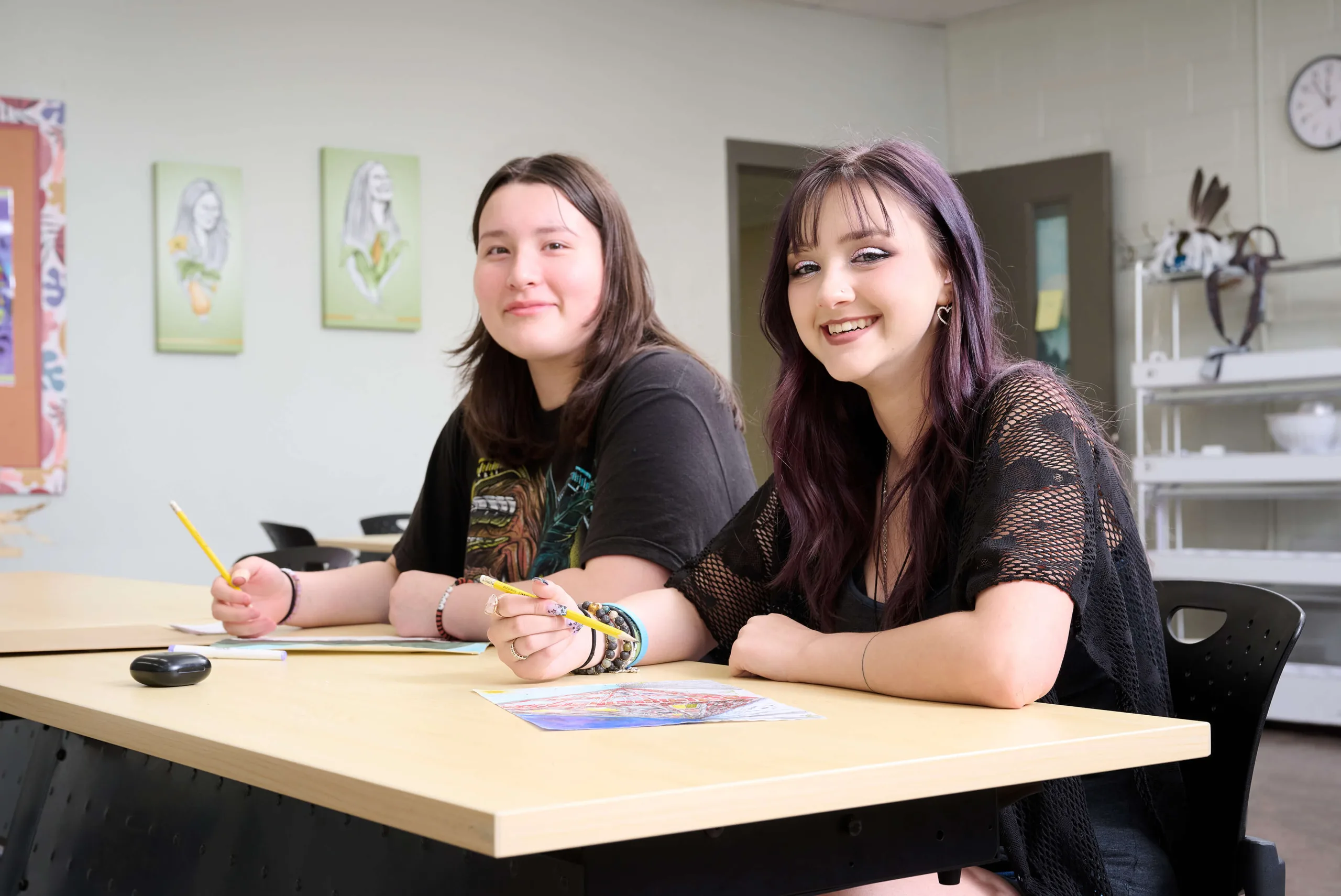 Young women smiling, sitting next to each other, having an art class
