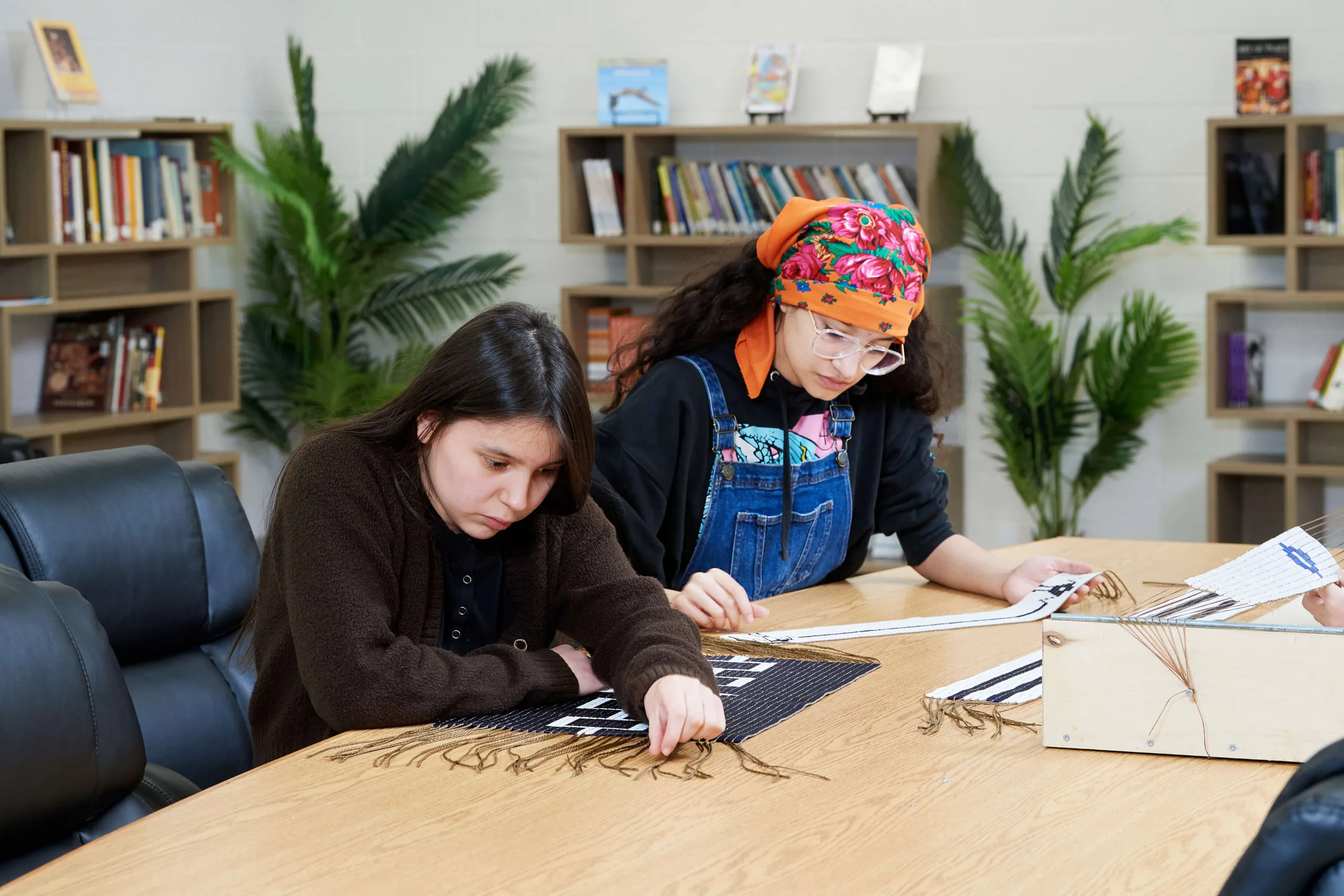 Young women are studying the ornaments on the piece of cloak.