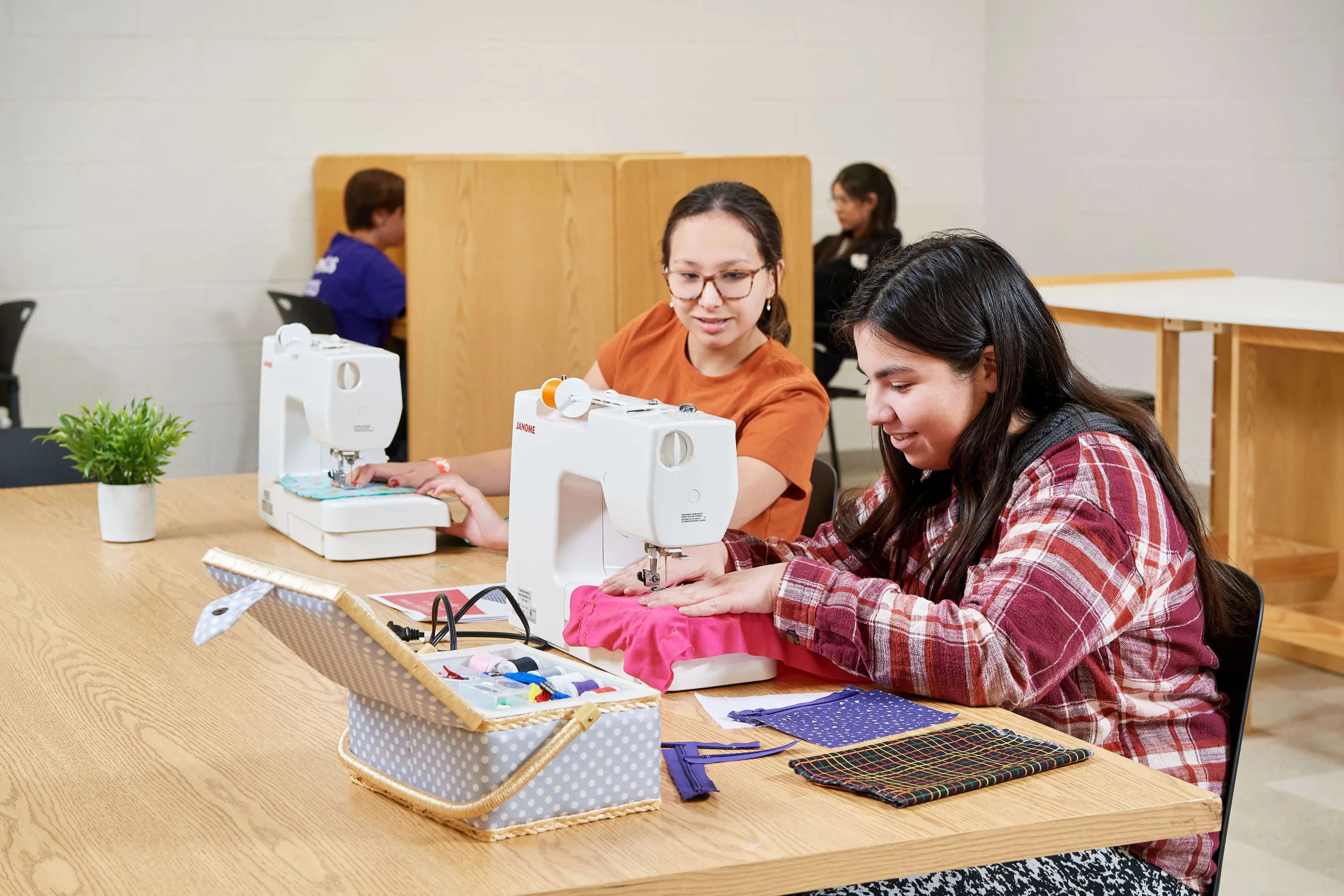 Young women having a class and practising sewing.