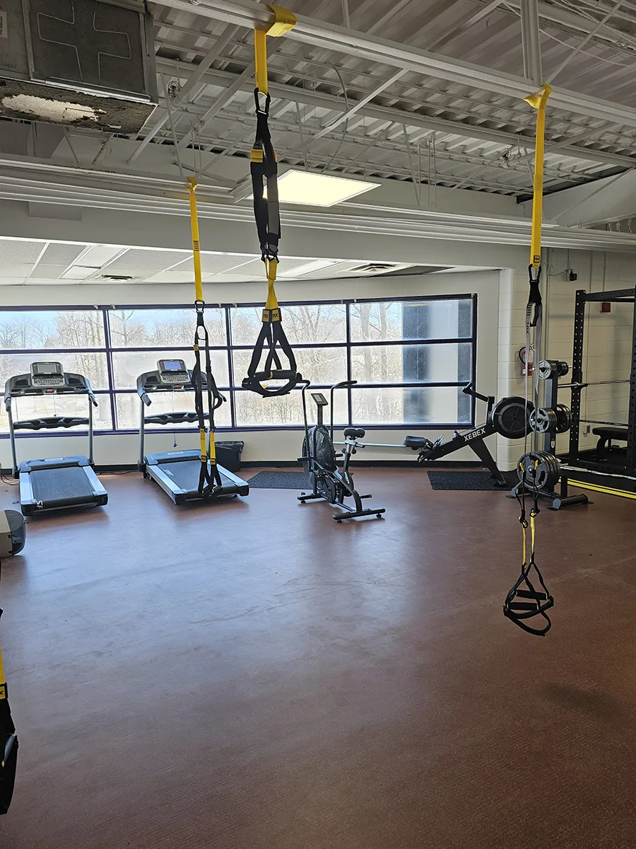 weight room with treadmills, hanging ropes and weight lifting equipment in from of large windows